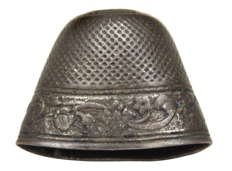 A silver thimble with the opening pressed almost flat.